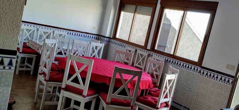Mesa redonda con sillas de madera y ventanales al fondo