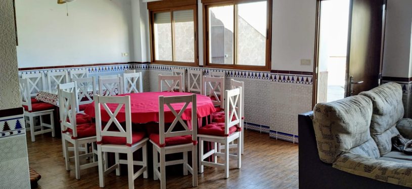 Mesa redonda con sillas de madera y ventanales al fondo