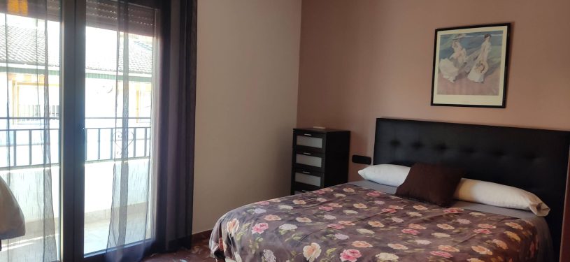 dormitorio con cama matrimonial y balcón