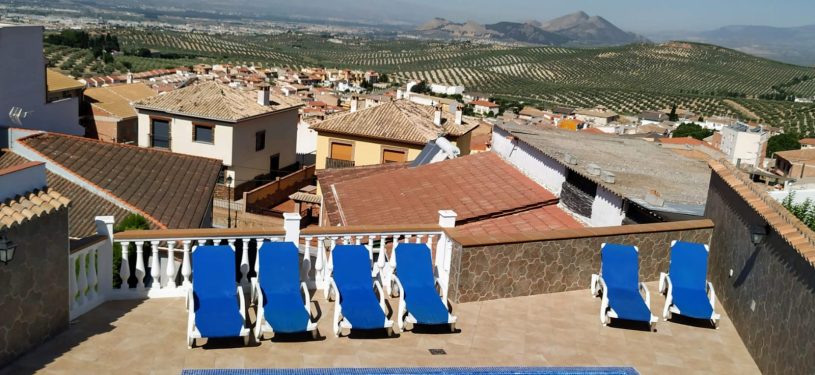 piscina exterior con mesas y vistas a la sierra